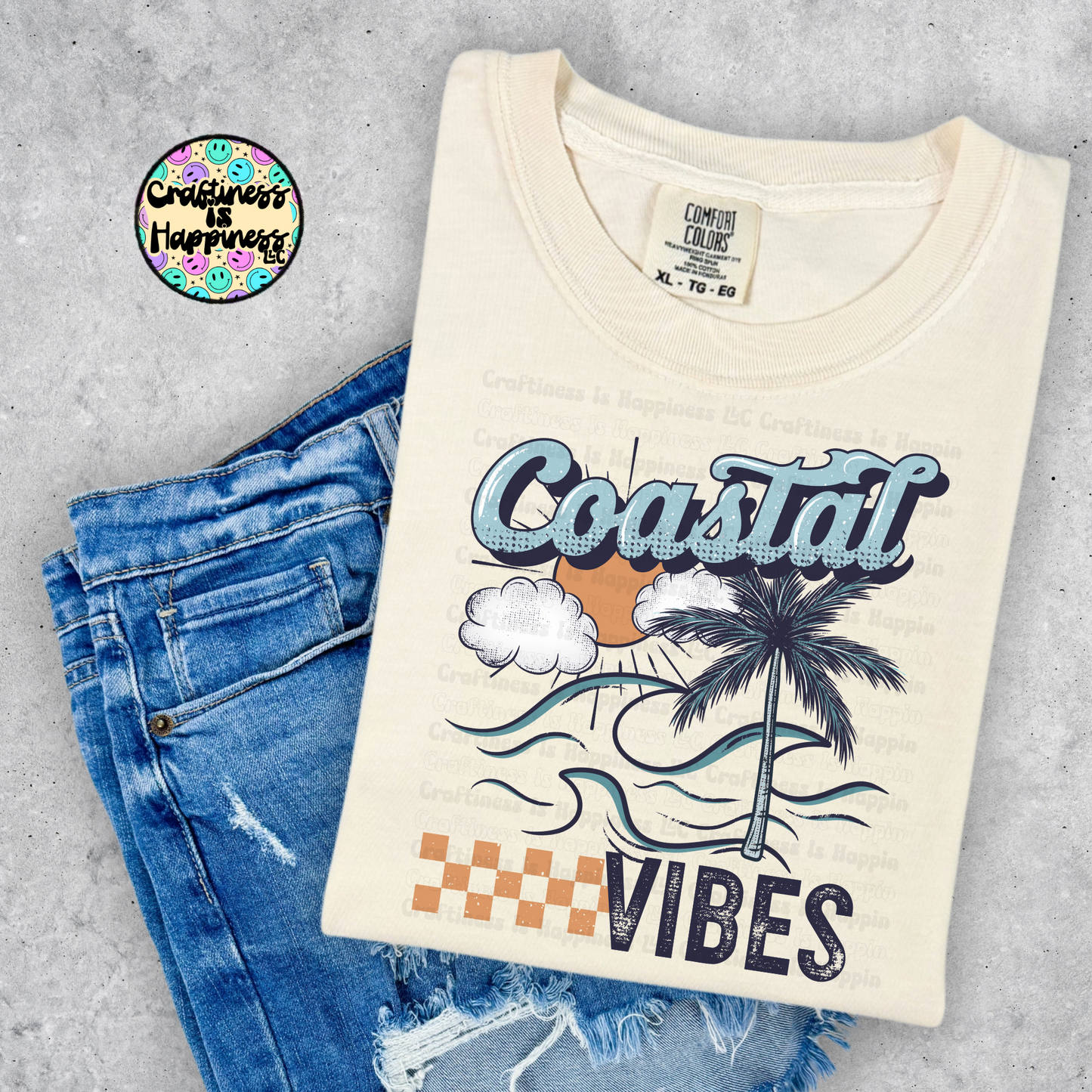 Beige t-shirt with 'Coastal Vibes' design on blue jeans against a gray background