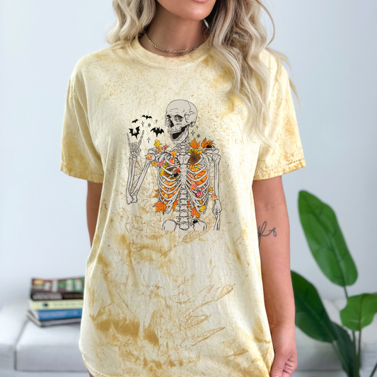 Heavyweight Color Blast short sleeve t-shirt with a skeleton full of fall lleaves and sunflowers, with bats flying high.