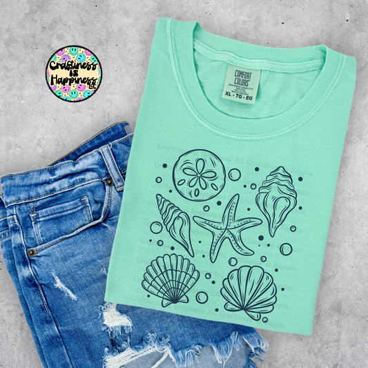 Island reef green t-shirt with beach-themed designs on a concrete surface with denim jeans.