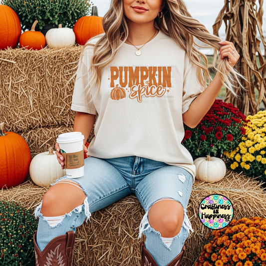 Woman wearing a 'Pumpkin Spice' shirt in a fall-themed setting with pumpkins and flowers.
