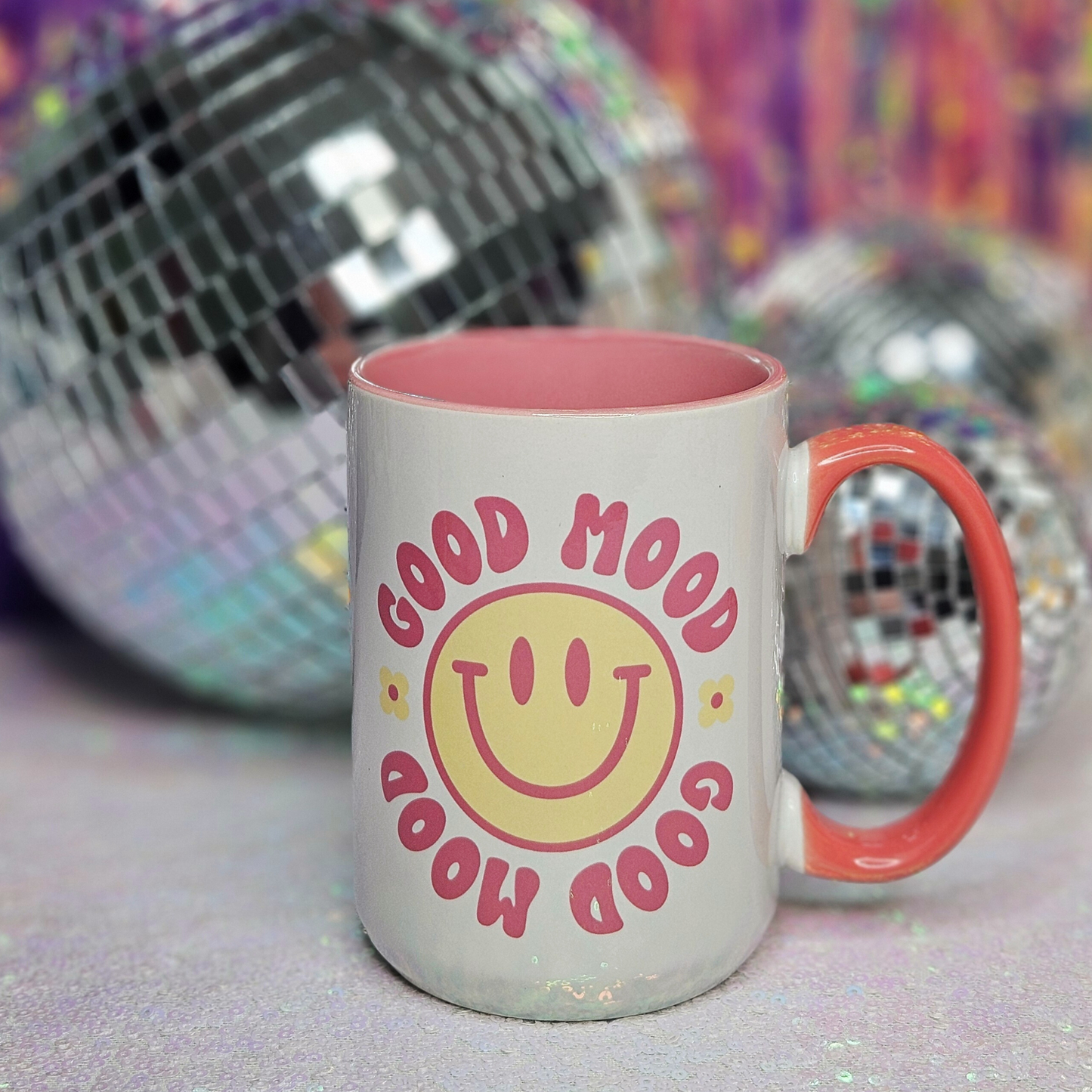 white 15oz mug "Good Mood" in pink text, yellow smiley face with pink trim, and yellow daisies, pink inside trim and pink handle 