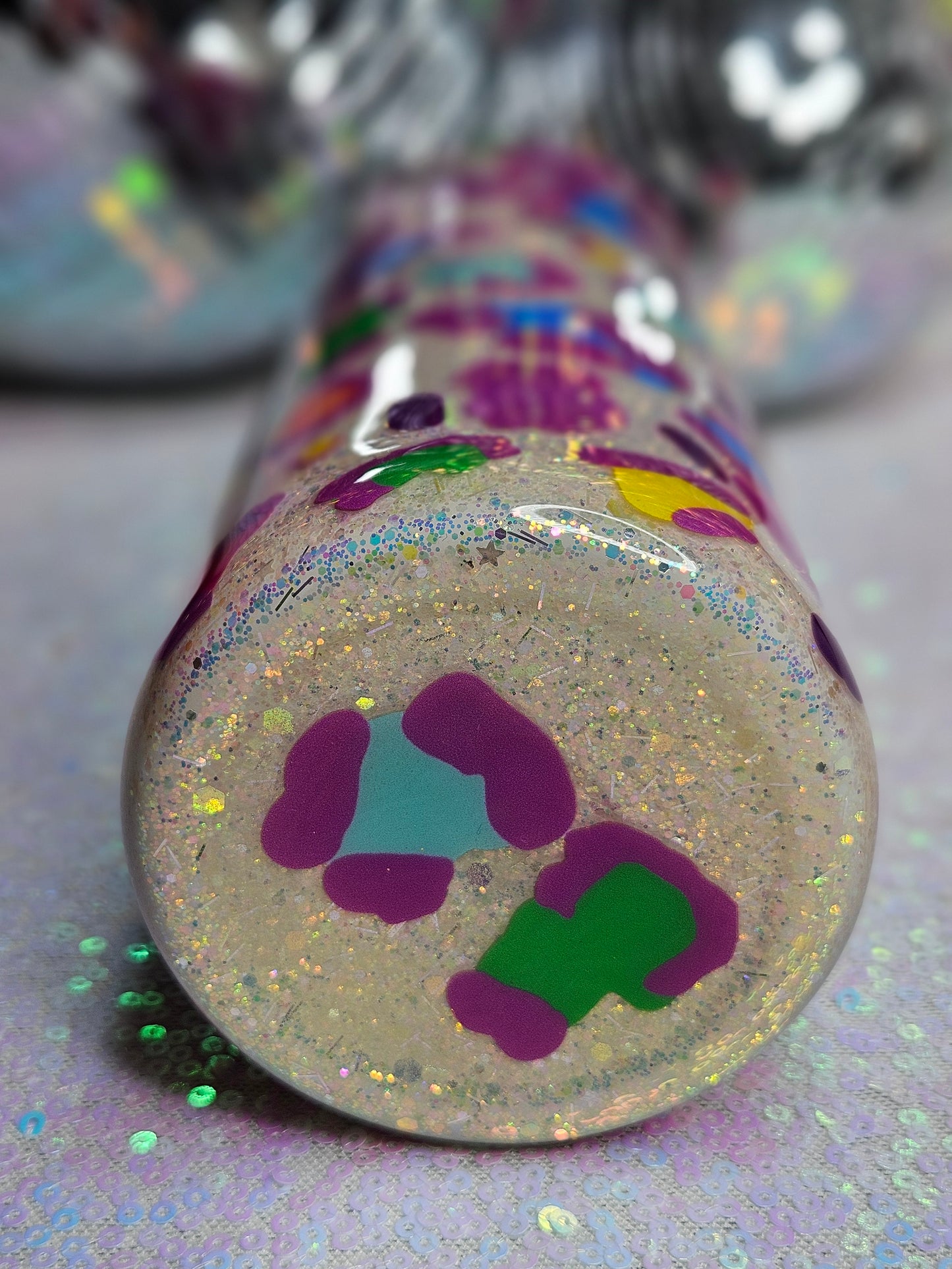 Bottom view of white glittered 20oz skinny tumbler wrapped with neon leopard spots. lid and straw are included.