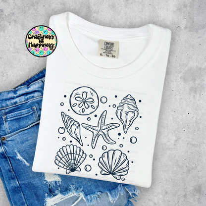 White t-shirt with black sea-themed designs on a concrete surface with jeans.