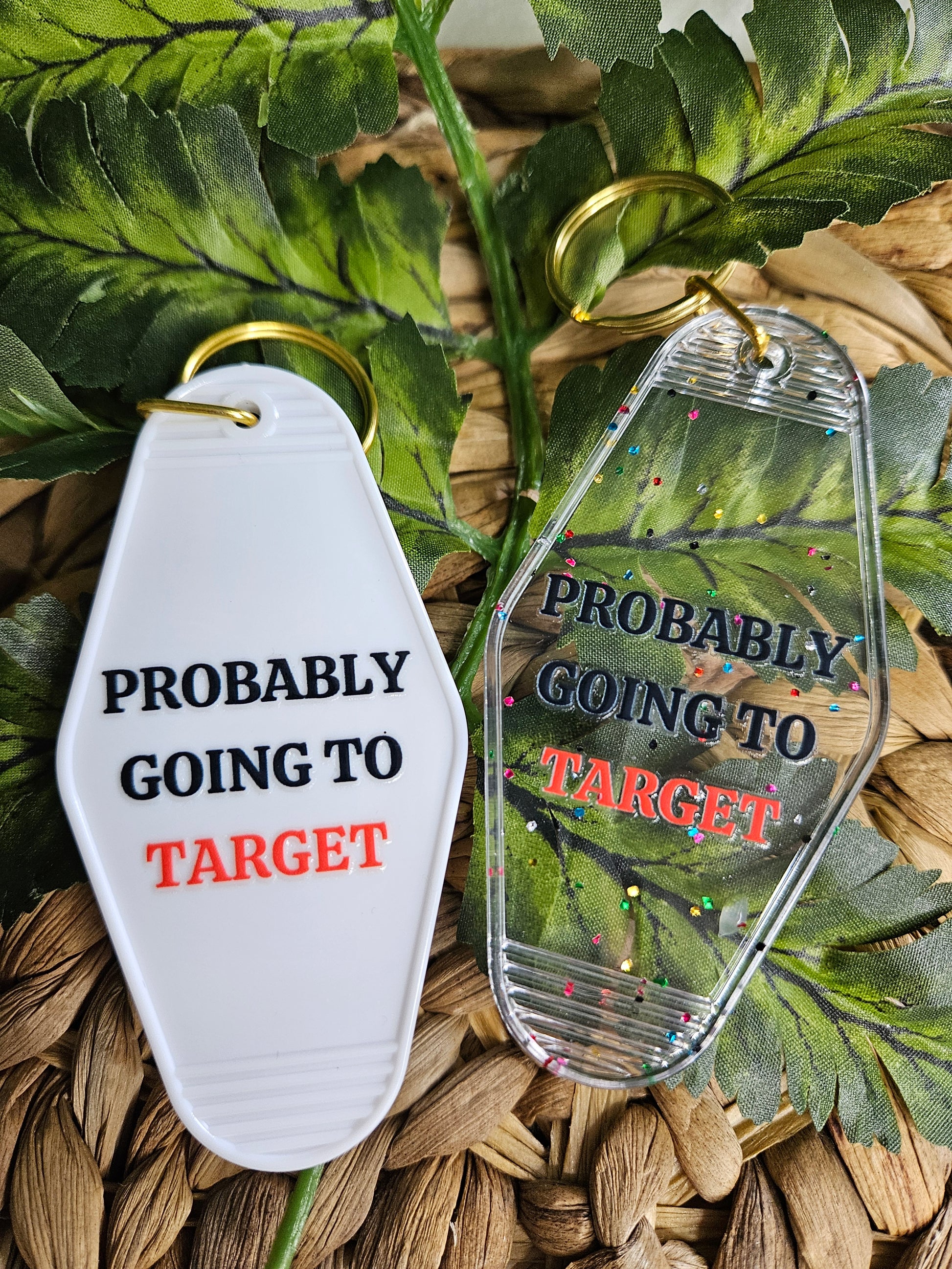 Available in a plain white or clear acrylic motel/ retro style keychain with confetti speckles. Decorated with a black font, except for the word "target", it is a coral color. UV DTF "Probably going to target". White and clear keychains have a gold colored hardware.