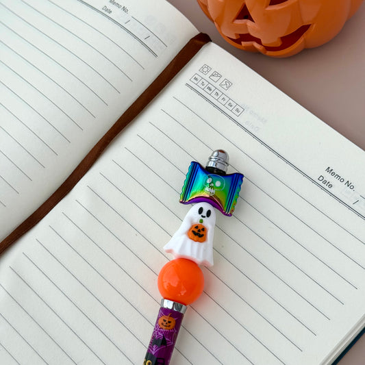Halloween-themed pen on a notebook with a pumpkin decoration in the background